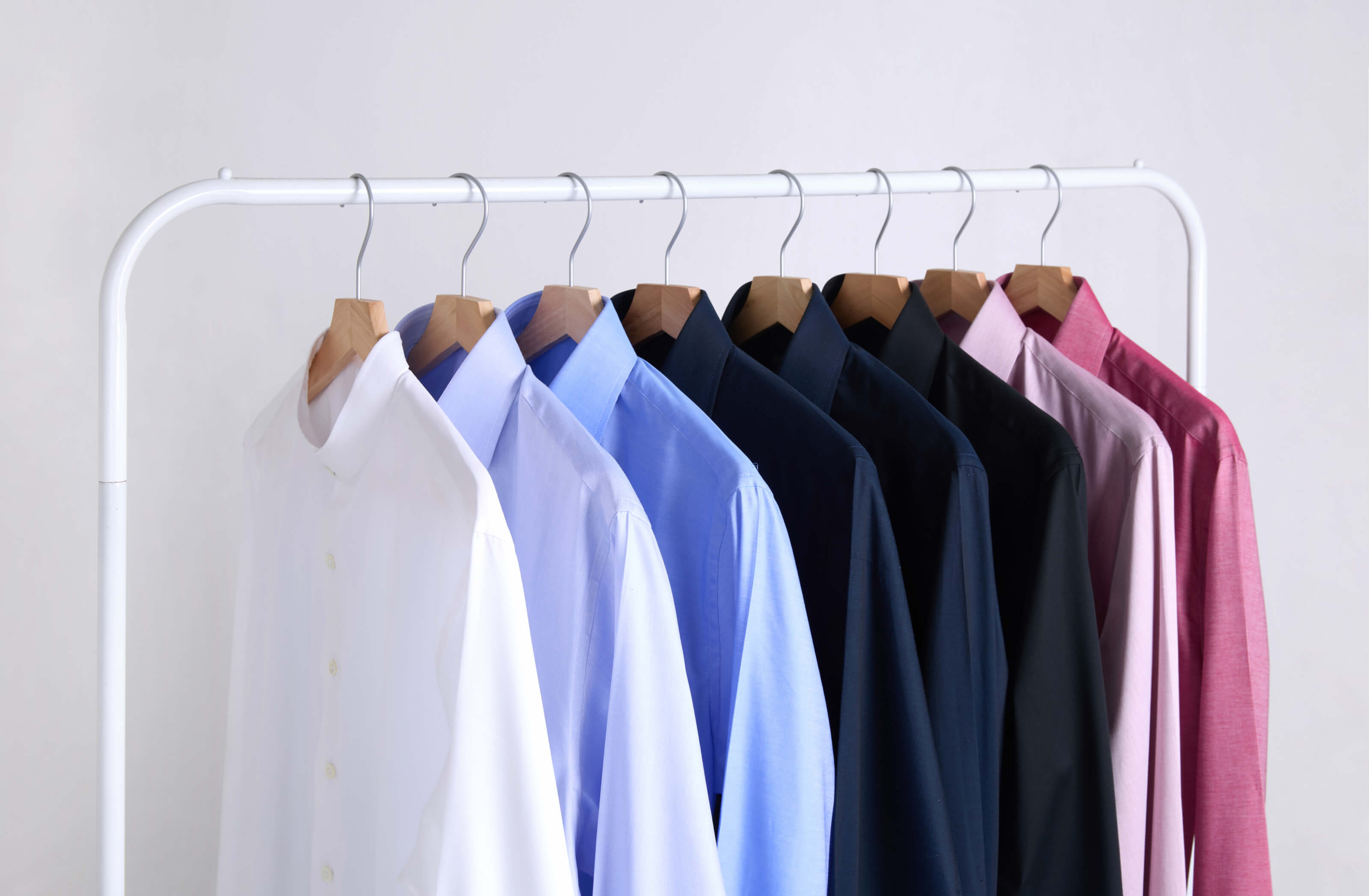 Row of colorful shirts on hangers against a white background